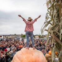 2016 Pumpkin Weigh Off Winner Cindy Tobeck atop her 1,910 lb winning gourd