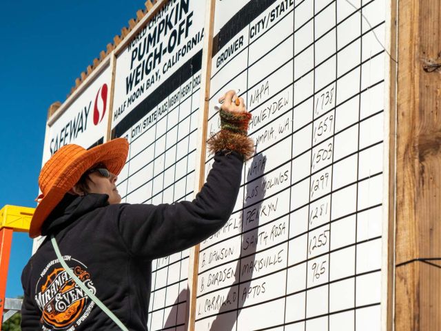 A volunteer carefully tracks names and weights on the results board